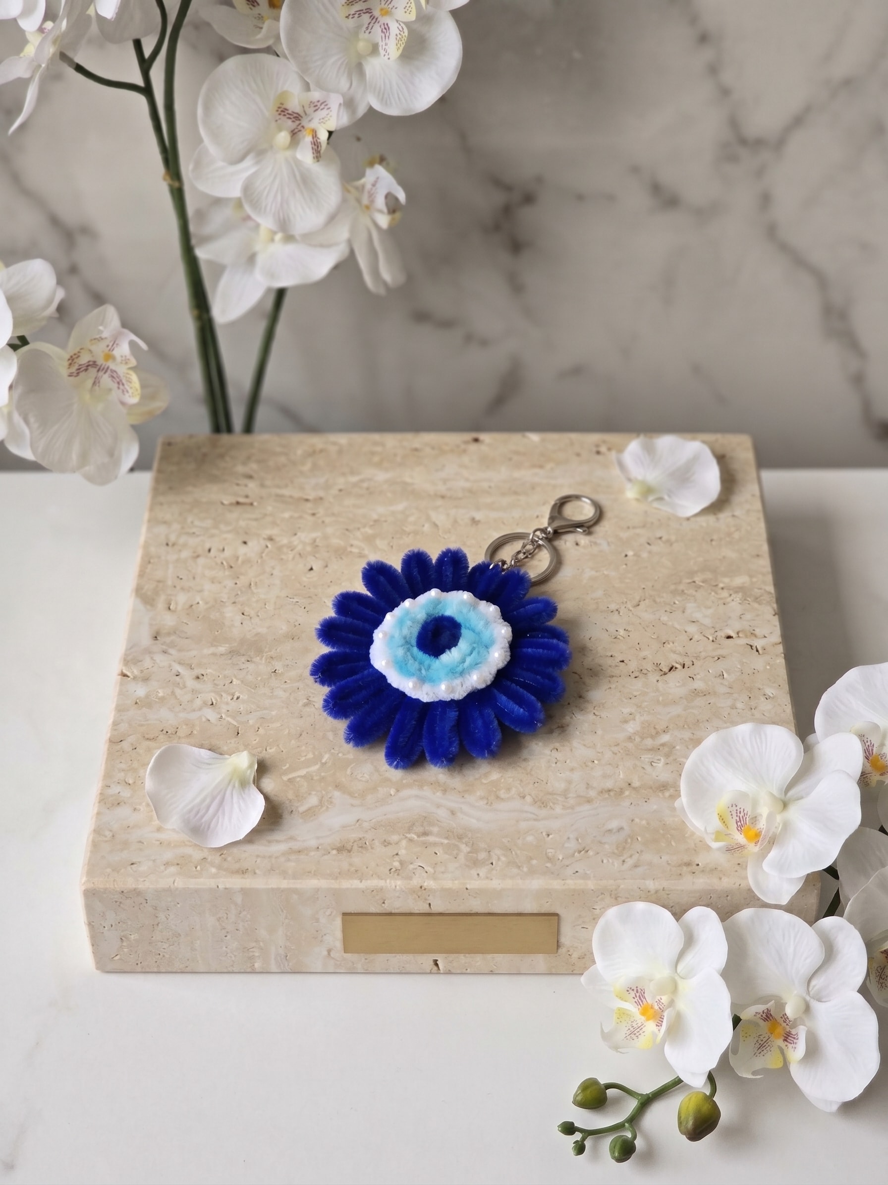 Blue Evil Eye Keychain β A handmade floral keychain featuring a bold royal blue flower design with an evil eye-inspired center and delicate pearl-style detailing. Perfect for keys, handbags, backpacks, and gifting.
